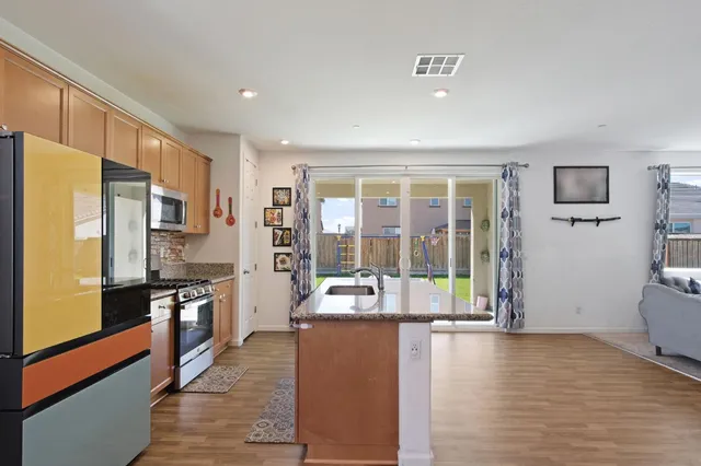 a large kitchen with kitchen island a large window a sink and stainless steel appliances
