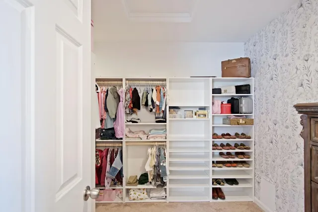 a view of walk in closet with clothes and shoes