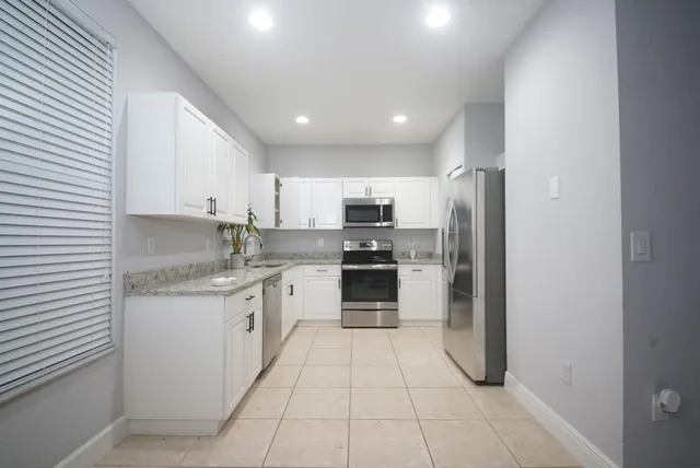 a kitchen with stainless steel appliances granite countertop a refrigerator and a stove top oven
