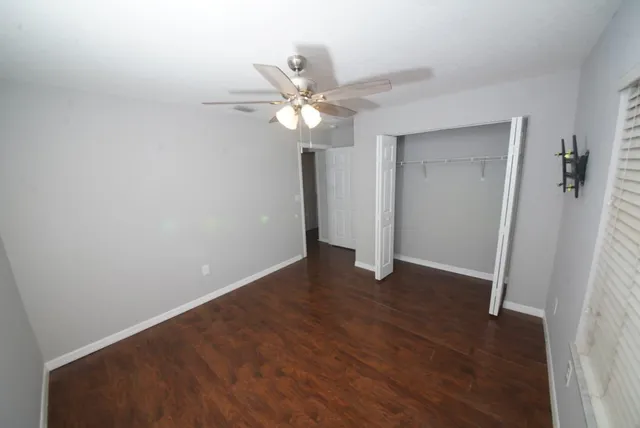 an empty room with wooden floor and ceiling fan