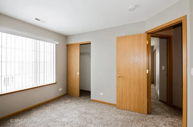 a view of an empty room with window and closet area