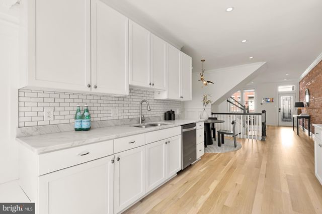 a kitchen with stainless steel appliances granite countertop a sink a stove top oven a chimney and cabinets