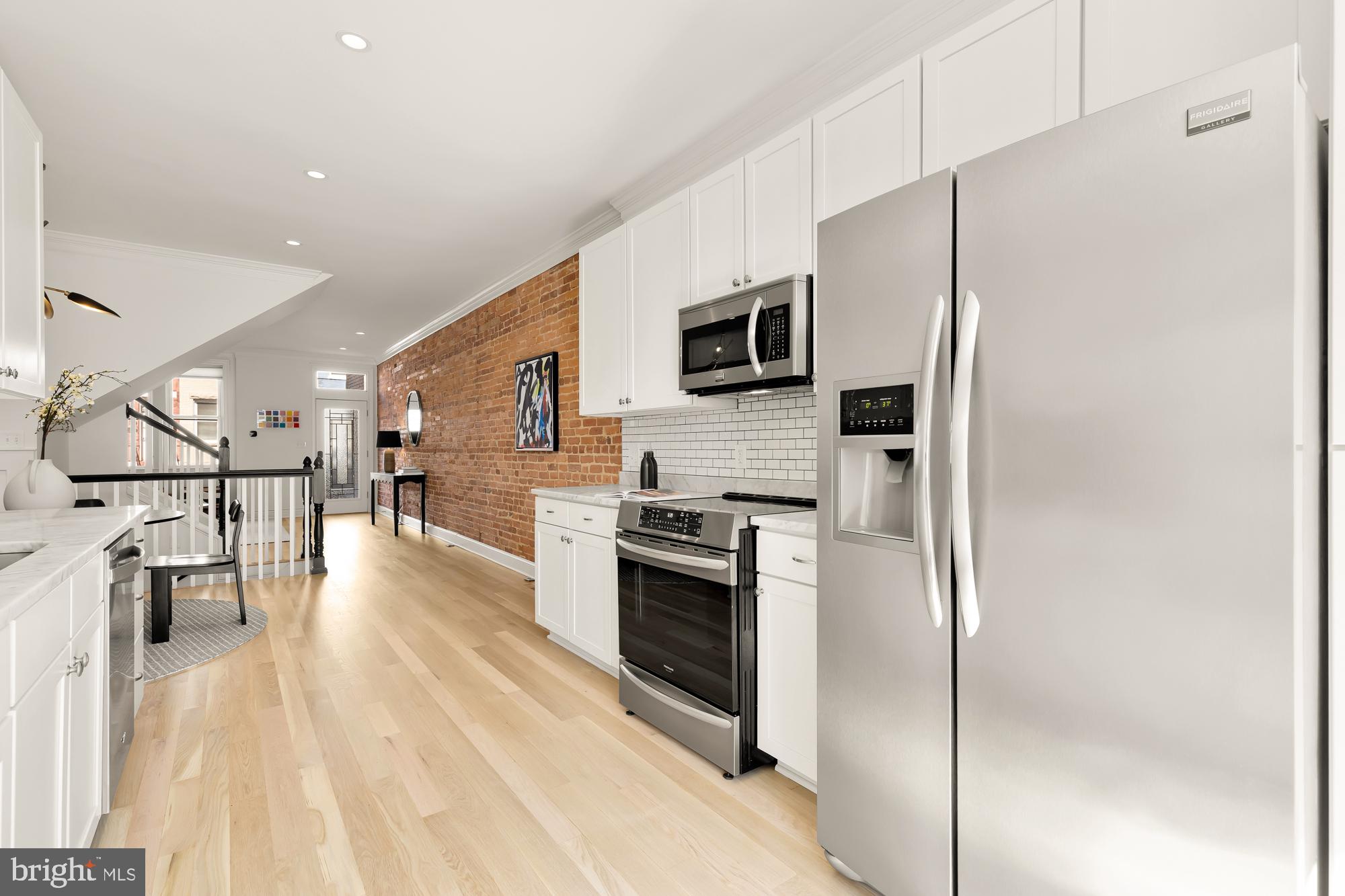 316 Elm Street Northwest Washington, DC 20001 - Photo 15 of 43 a kitchen with stainless steel appliances a refrigerator a stove top oven a sink dishwasher and white cabinets with wooden floor