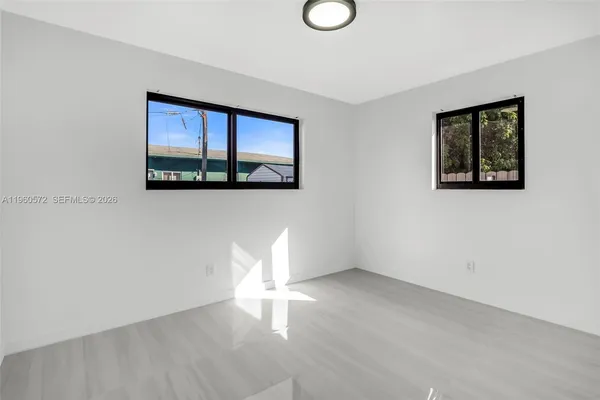 a view of an empty room with a window and wooden floor