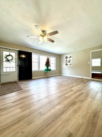 a view of an empty room with a window and wooden floor