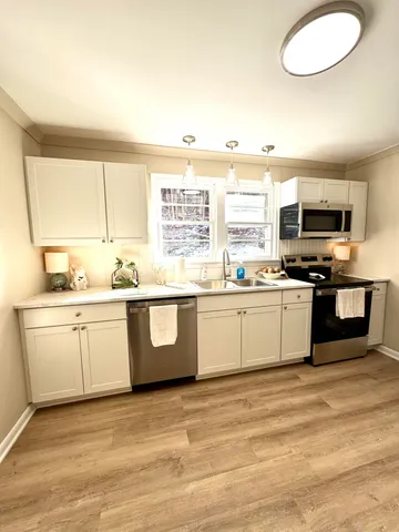 a kitchen with granite countertop a sink cabinets stainless steel appliances and a window