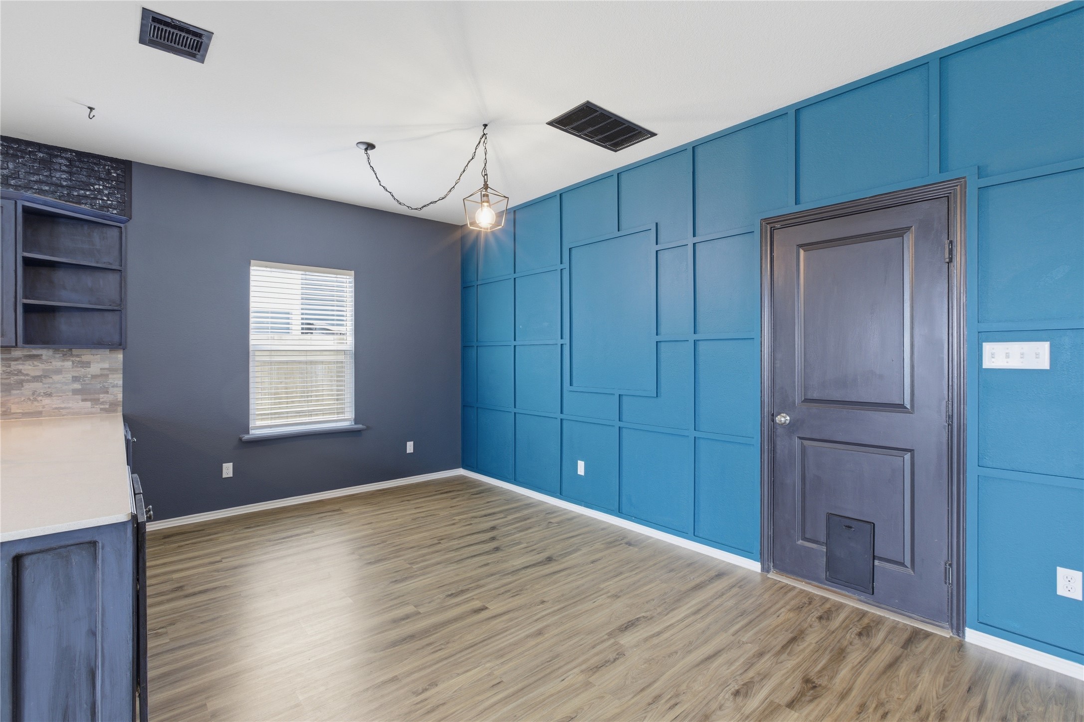 116 Night Riders Way Jarrell, TX 76537 - Photo 19 of 40 Dining area featuring a modern geometric accent wall, wood-finish flooring, and a contemporary pendant light fixture