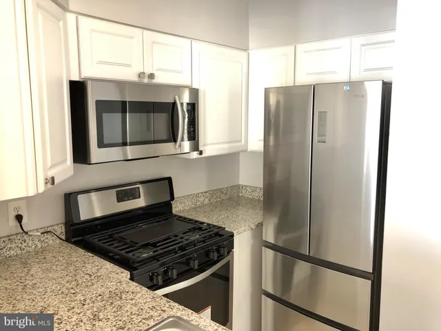 a kitchen with stainless steel appliances granite countertop a refrigerator and a sink