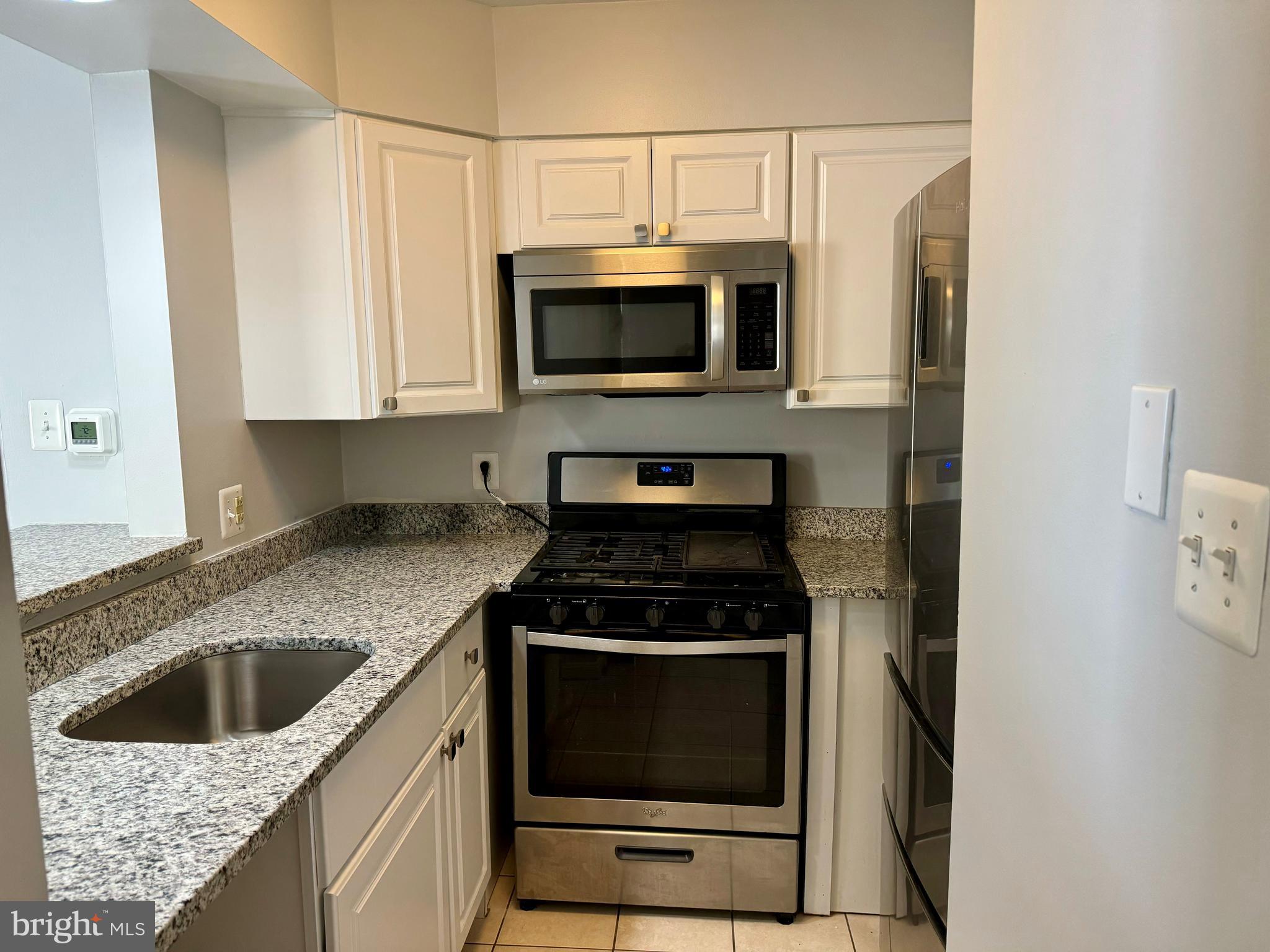 4733 Bradley Boulevard, Unit 11 Chevy Chase, MD 20815 - Photo 4 of 10 a kitchen with stainless steel appliances granite countertop a stove a microwave and a sink