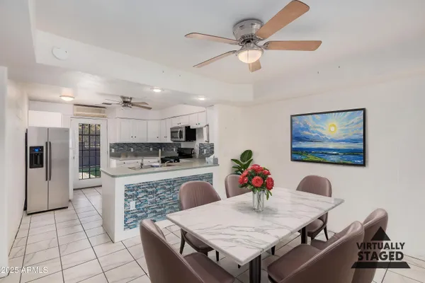 a living room with stainless steel appliances furniture a dining table and kitchen view