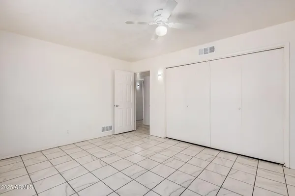 an empty room with windows and fan
