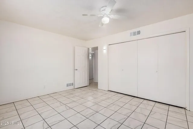 an empty room with windows and fan