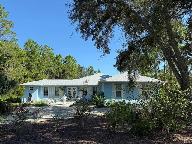a view of a white house next to a yard with potted plants