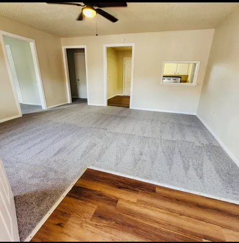 a view of an empty room with wooden floor and windows