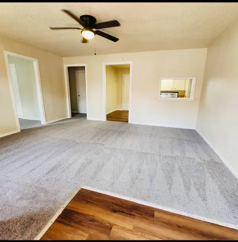 a view of a big room with wooden floor and windows