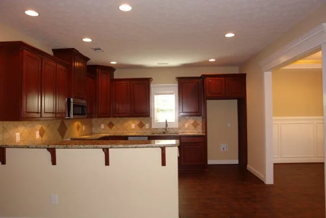 a kitchen with kitchen island granite countertop wooden cabinets and refrigerator
