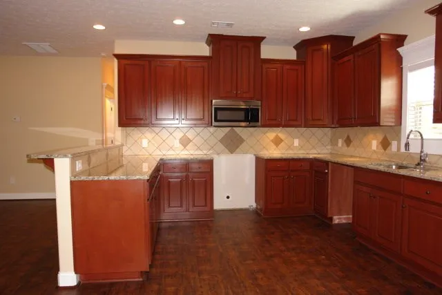 a kitchen with stainless steel appliances granite countertop white cabinets a refrigerator and a sink