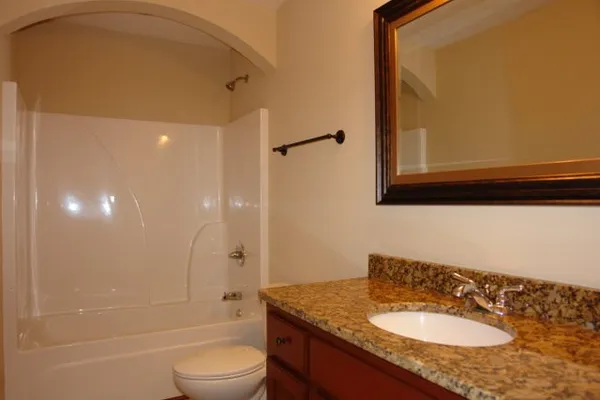 a bathroom with a granite countertop sink toilet and shower