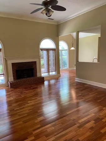 an empty room with wooden floor fireplace and a window