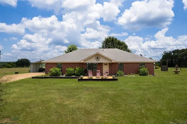 a view of a house with a big yard and a large tree