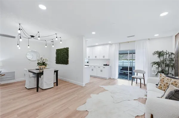 a living room with furniture a dining table and kitchen view with wooden floor