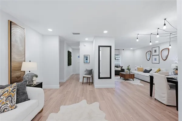 a living room with furniture kitchen view and a wooden floor