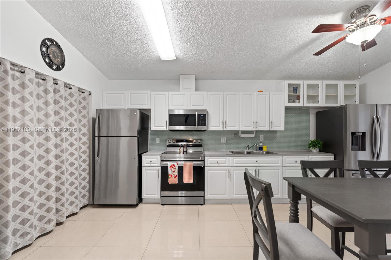 6919 West 29th Way Hialeah, FL 33018 - Photo 7 of 23 a kitchen with stainless steel appliances granite countertop a refrigerator a stove a microwave oven a sink with island and chairs