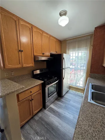 a kitchen with granite countertop stainless steel appliances a stove top oven sink and cabinets