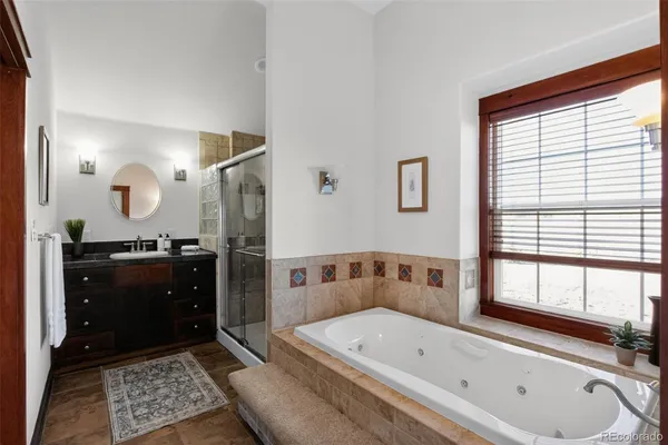 a bathroom with a tub a double vanity sink and mirror