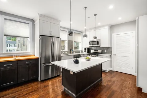 a kitchen with kitchen island granite countertop a sink appliances and wooden floor