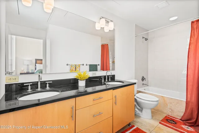 a bathroom with a granite countertop sink a toilet a mirror and shower