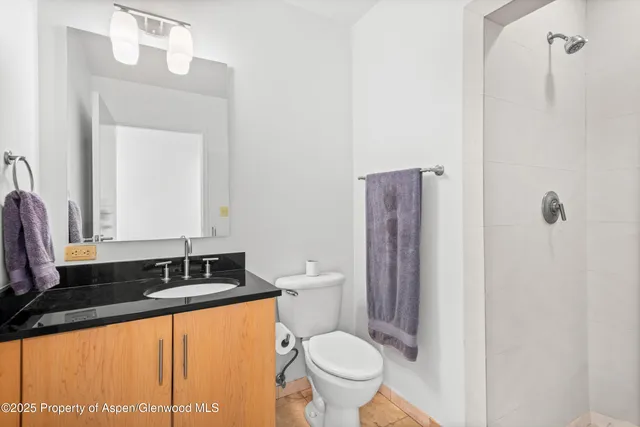 a bathroom with a granite countertop sink mirror vanity and toilet