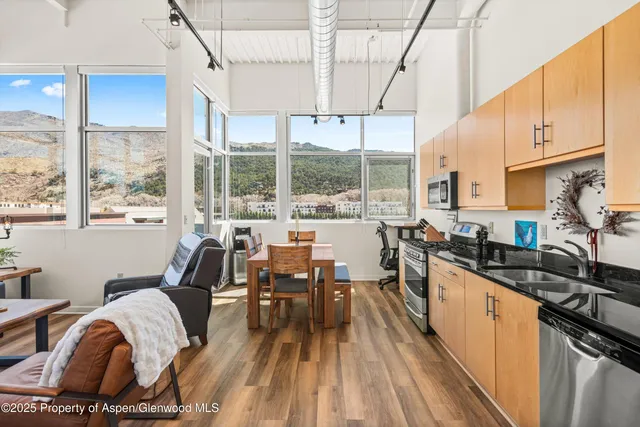 a open kitchen with granite countertop a stove a sink a dining table and chairs with wooden floor