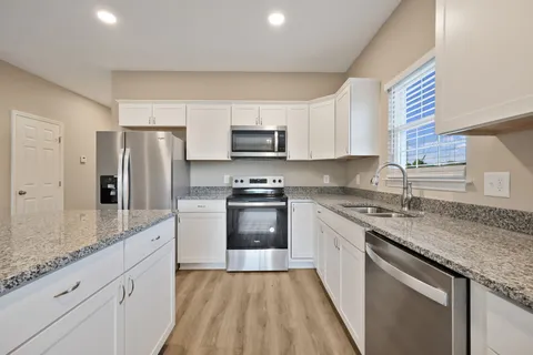 a kitchen with granite countertop a refrigerator stove top oven and sink
