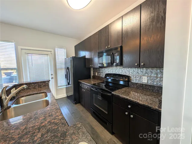 a kitchen with granite countertop a stove a sink and a refrigerator