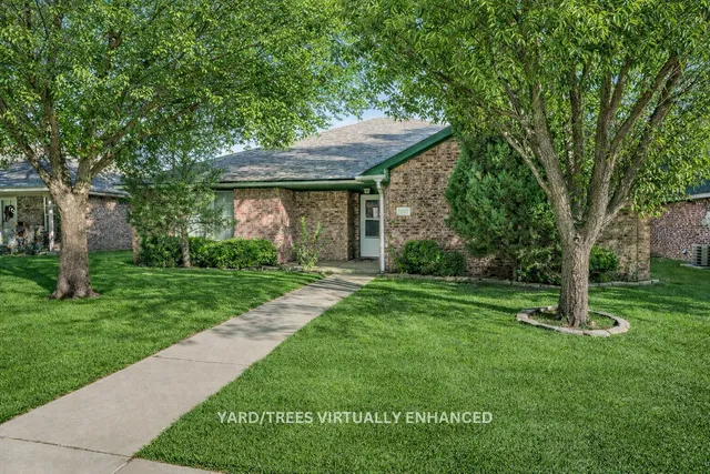 a view of a yard in front of a house with a large tree