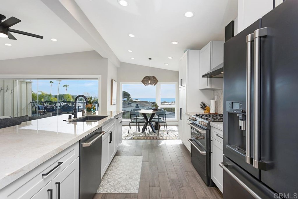 620 West Solana Circle, Unit 3A Solana Beach, CA 92075 - Photo 2 of 37 a kitchen with stainless steel appliances granite countertop a refrigerator stove oven and a large window with wooden floor
