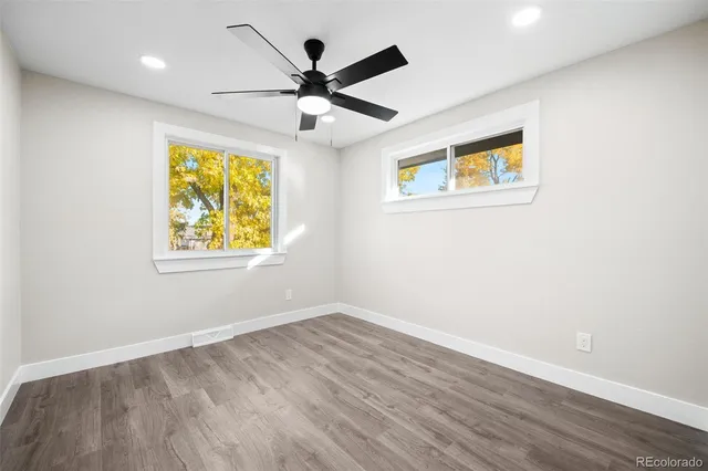 an empty room with wooden floor and ceiling fan
