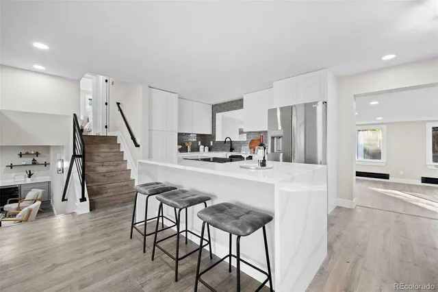 a kitchen with stainless steel appliances a refrigerator a stove a sink dishwasher and white cabinets with wooden floor