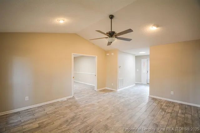 a view of an empty room and a chandelier fan