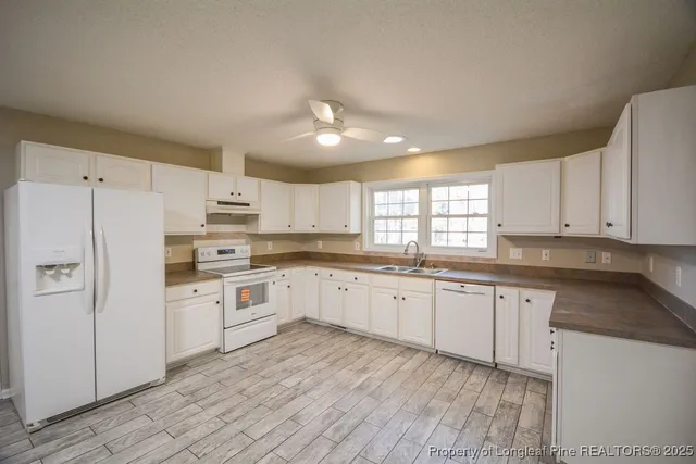 a kitchen with granite countertop white cabinets and white appliances