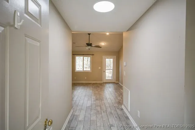 a view of hallway with window and wooden floor