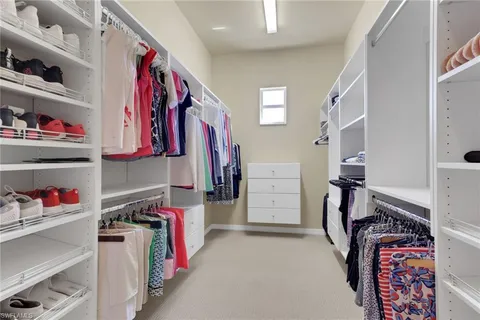 a view of walk in closet with clothes and shoes