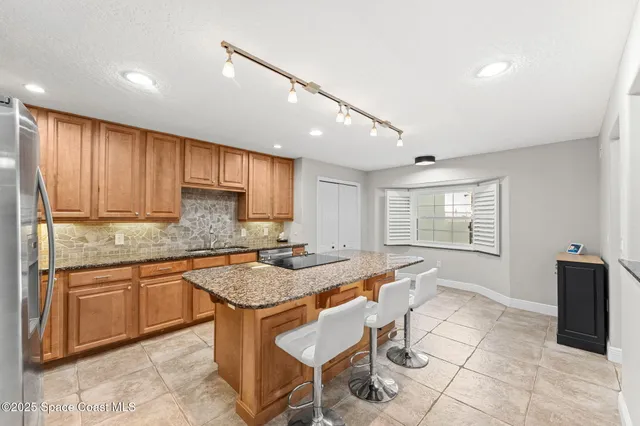 a kitchen with kitchen island granite countertop a refrigerator and a stove top oven