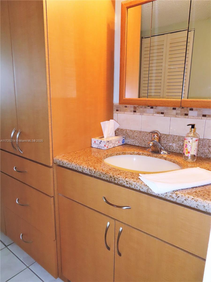 5701 Collins Avenue, Unit 1011 Miami Beach, FL 33140 - Photo 43 of 50 a bathroom with a granite countertop sink and a mirror