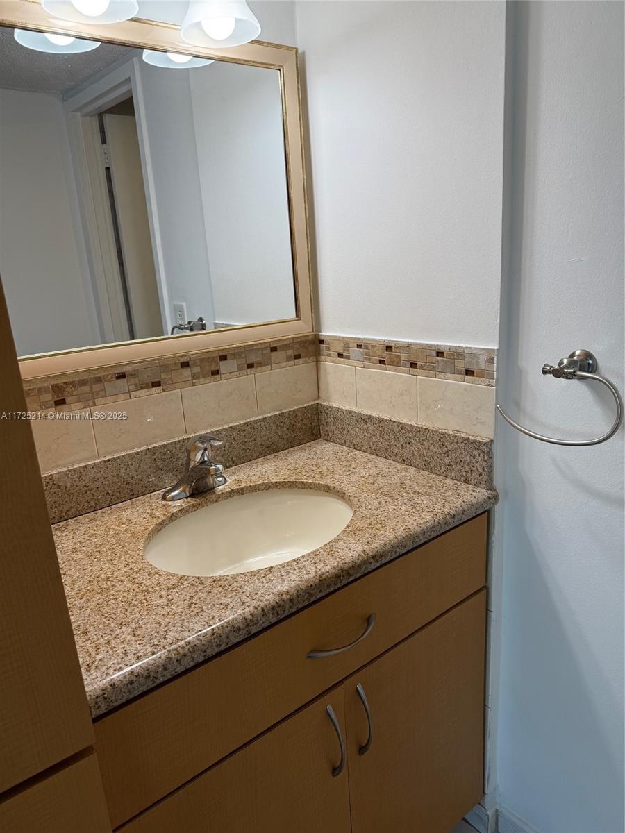 5701 Collins Avenue, Unit 1011 Miami Beach, FL 33140 - Photo 48 of 50 a bathroom with a granite countertop sink and a mirror
