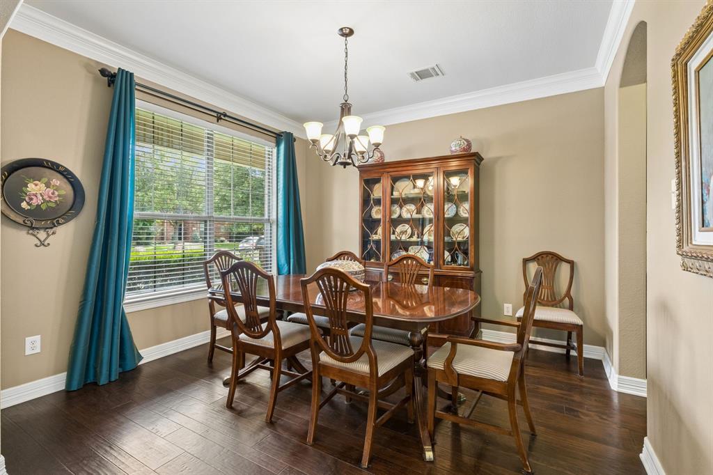960 Remuda Road Frisco, TX 75033 - Photo 7 of 39 Formal dining space featuring dark wood-finish flooring, a large window with horizontal blinds, a traditional chandelier, crown molding, and a cased opening