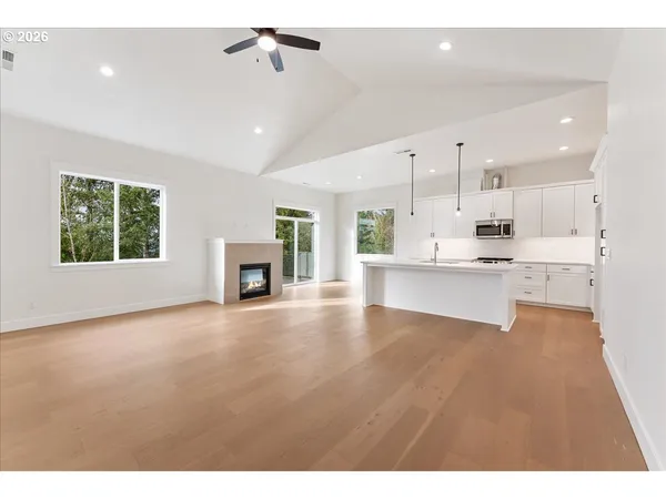 a view of an empty room with a window and kitchen view