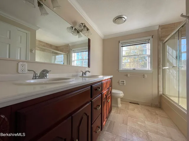 a bathroom with a granite countertop sink a toilet and a window
