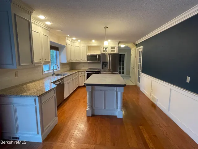 a large kitchen with wooden floors and stainless steel appliances